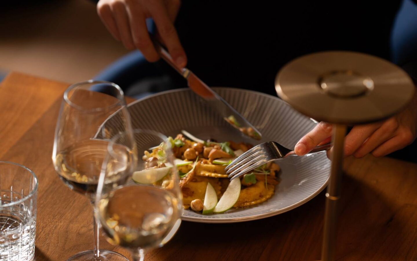 a person cutting food on a plate with a knife and fork